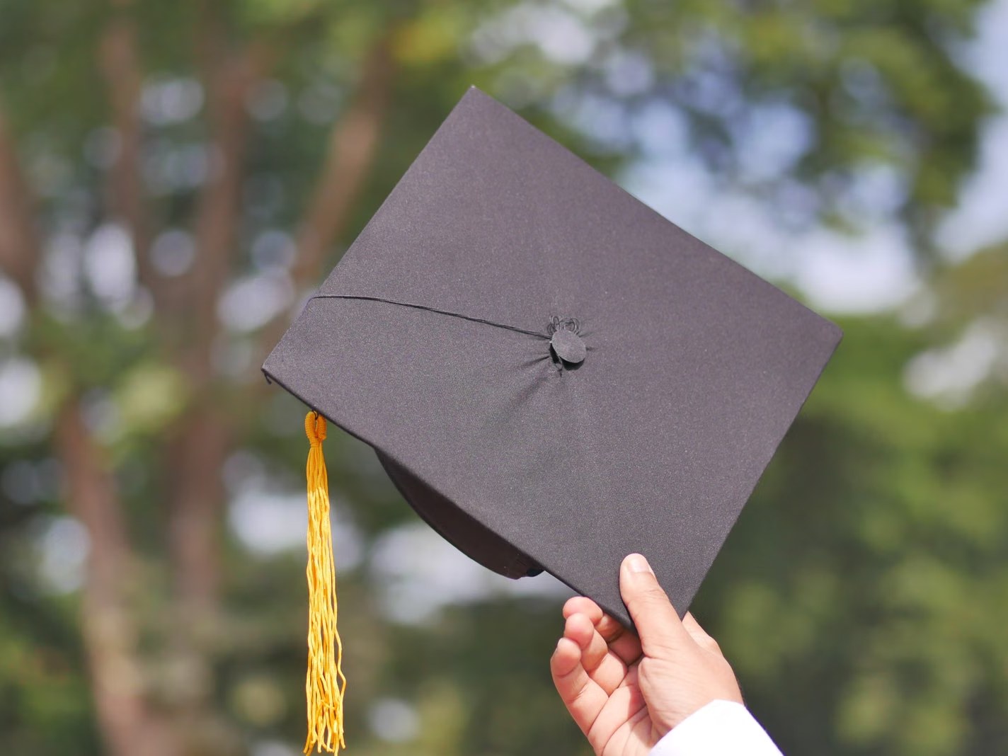 Topi wisuda diangkat ke udara — merayakan kelulusan